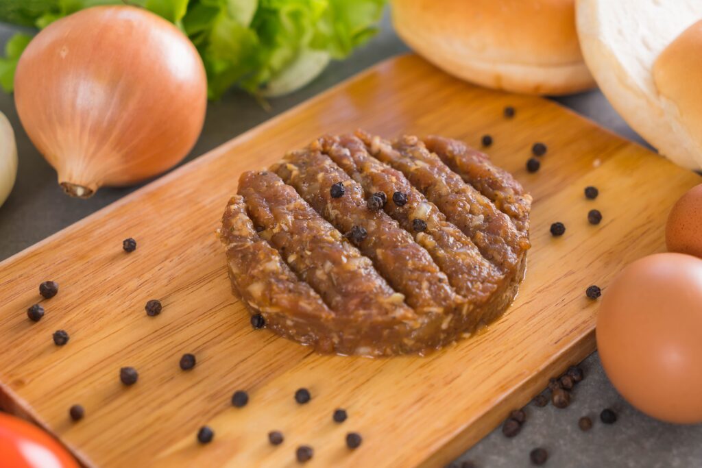 Close-up of turkey sausage patties being pan-fried in a cast-iron skillet, with a golden-brown sear on the surface.