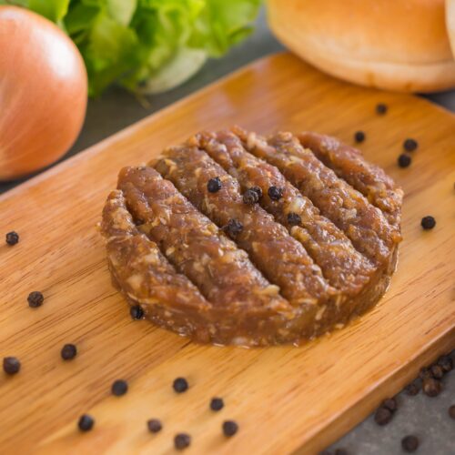 Close-up of turkey sausage patties being pan-fried in a cast-iron skillet, with a golden-brown sear on the surface.