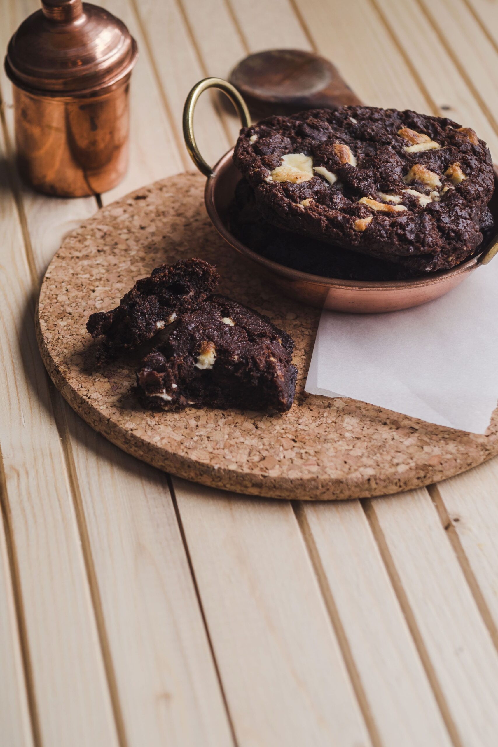 Close-up of a Brownie-Cookie showing a gooey chocolate center and crisp cookie edges, topped with chocolate chips, served on a wooden plate.