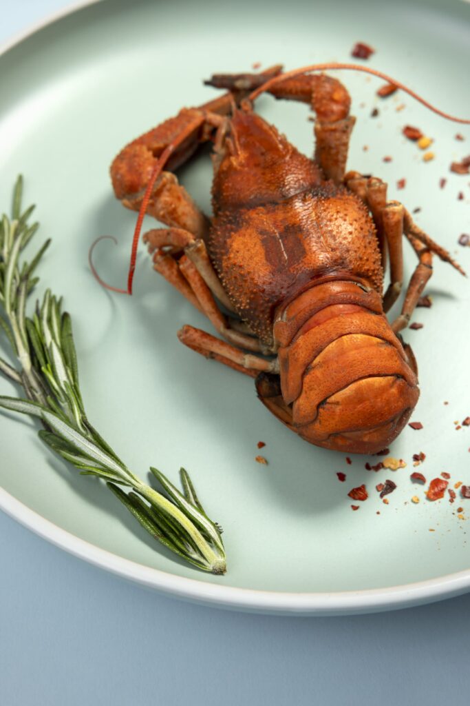 Step-by-step demonstration of cutting a lobster tail shell to expose the meat.