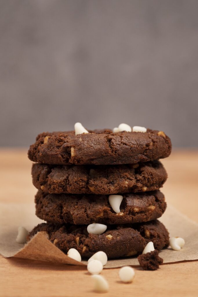 Close-up of a Brownie-Cookie showing a gooey chocolate center and crisp cookie edges, topped with chocolate chips, served on a wooden plate.