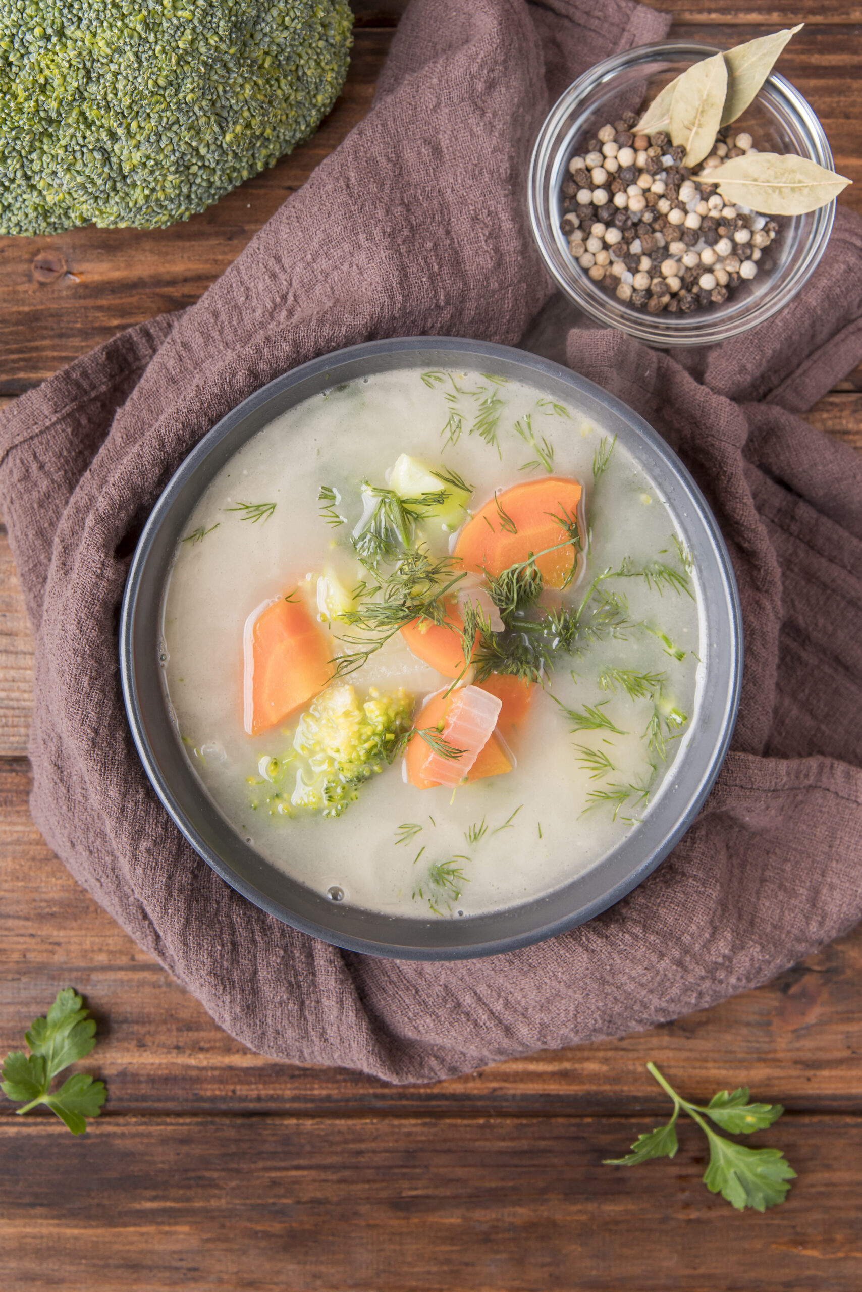 A bowl of creamy salmon soup served with a slice of crusty bread on a wooden table, showcasing the rich texture of the soup and fresh herbs as garnish