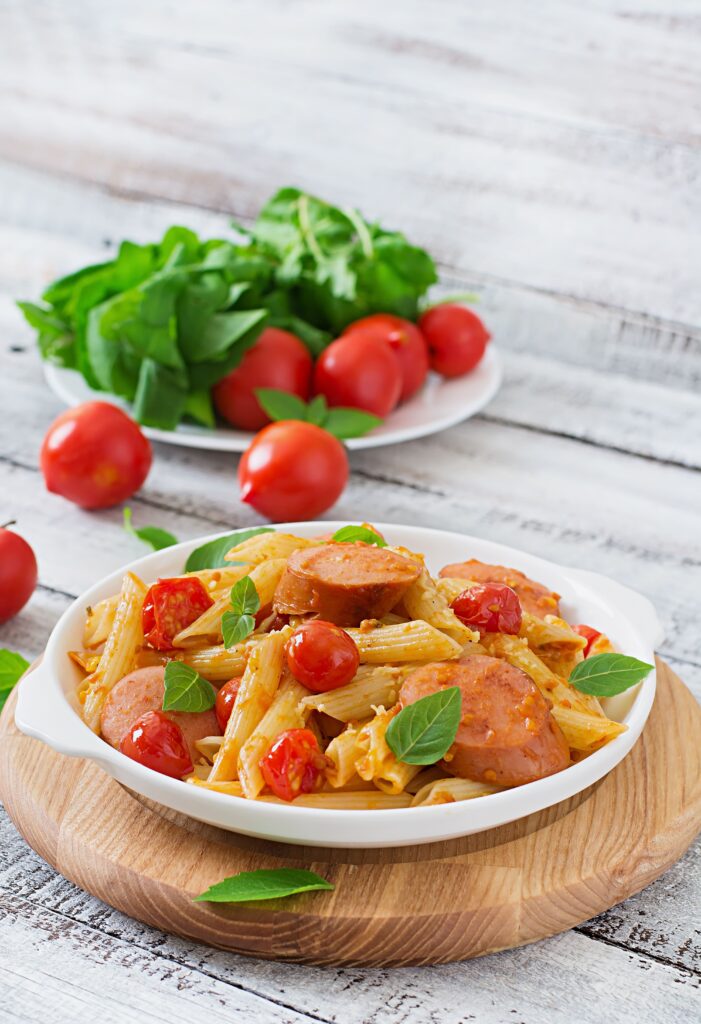 Close-up of tender pasta and sliced smoked sausage coated in a rich, creamy sauce.