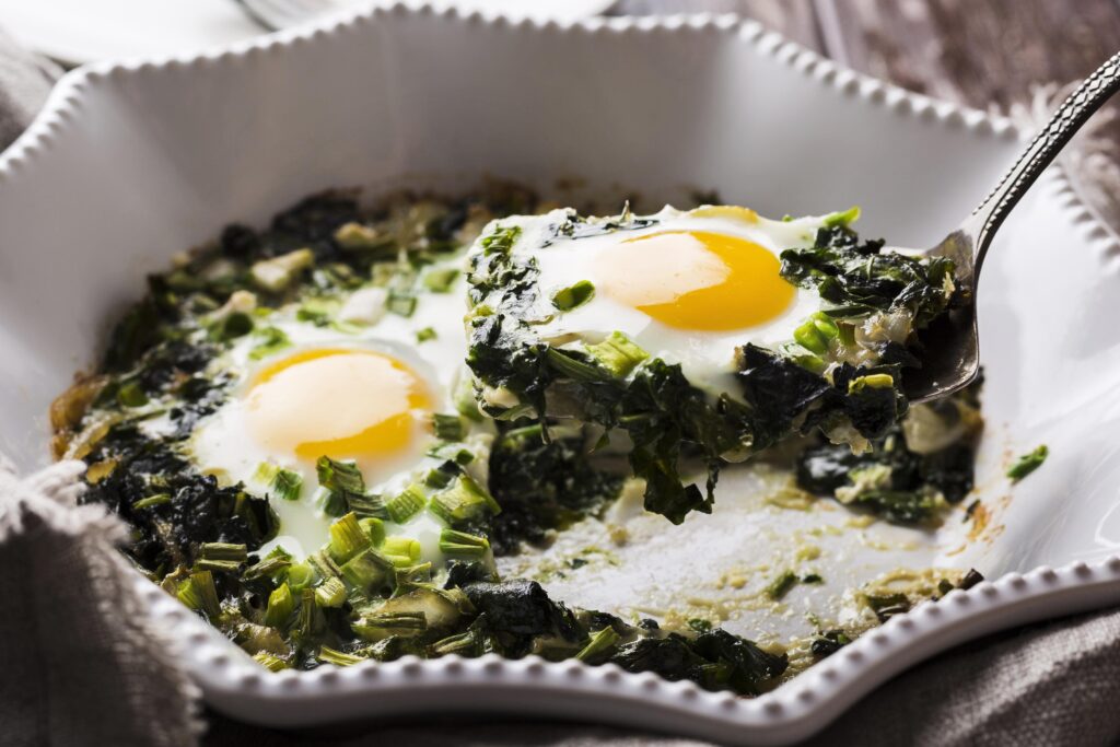 Golden savory muffins made with  eggs and peas, and diced vegetables, displayed on a white plate with a side of yogurt-mint dipping sauce.