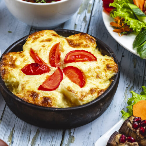 "Freshly baked cottage cheese in a casserole dish with golden edges and sprinkled herbs."