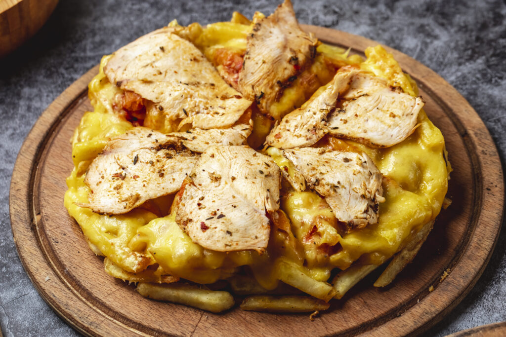 A close-up of Philly Cheese Chicken topped with melted Provolone cheese, sautéed bell peppers, and onions served on a white plate.