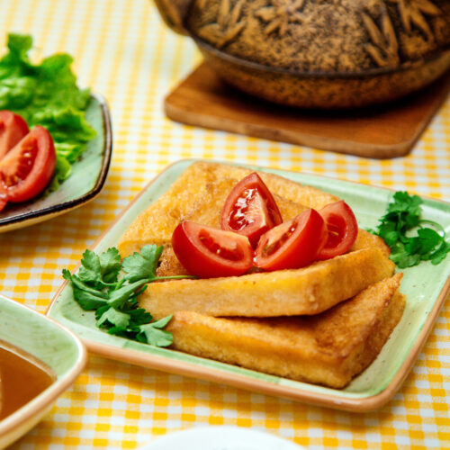 Golden brown cheesy hash browns served on a white plate with a garnish of fresh parsley