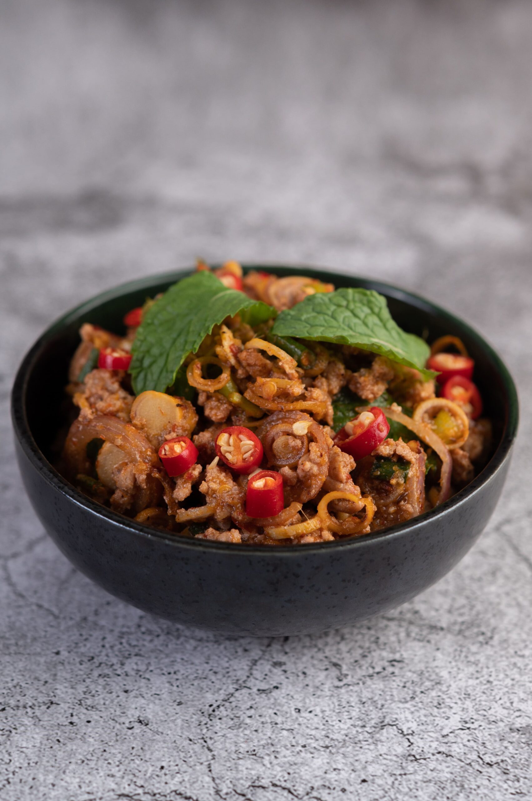 A plate of Beef Pad Thai with tender slices of beef, chewy rice noodles, and garnishes of crushed peanuts, lime wedges, and fresh cilantro.