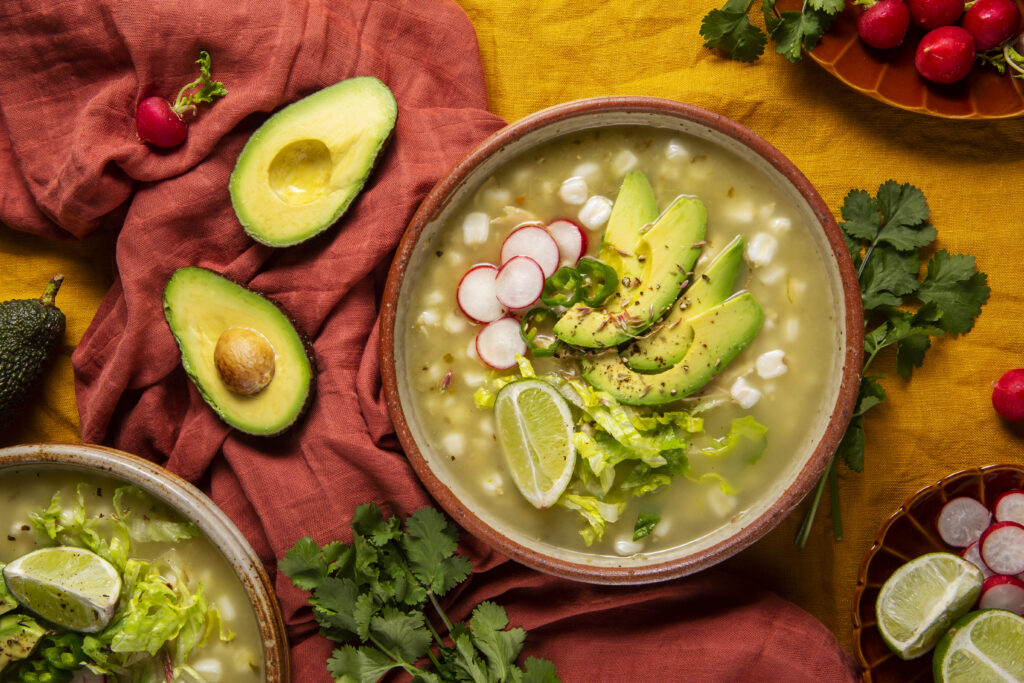 Close-up of traditional Mexican chicken soup with hearty chunks of chicken, diced potatoes, and fresh vegetables, served with a side of warm tortillas and lime wedges.