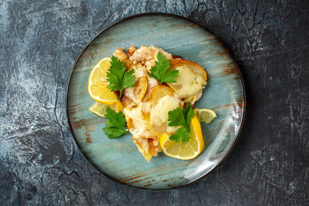 A plate of golden-seared scallops served over creamy lemon butter orzo, garnished with fresh parsley and a lemon wedge.