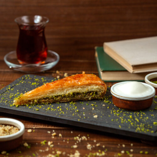 A close-up view of a plate of pistachio baklava, with golden