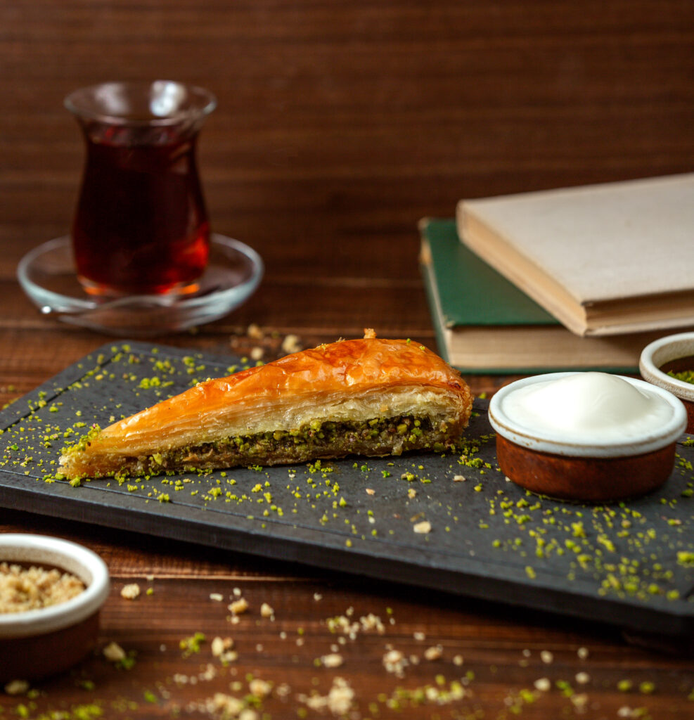 A close-up view of a plate of pistachio baklava, with golden